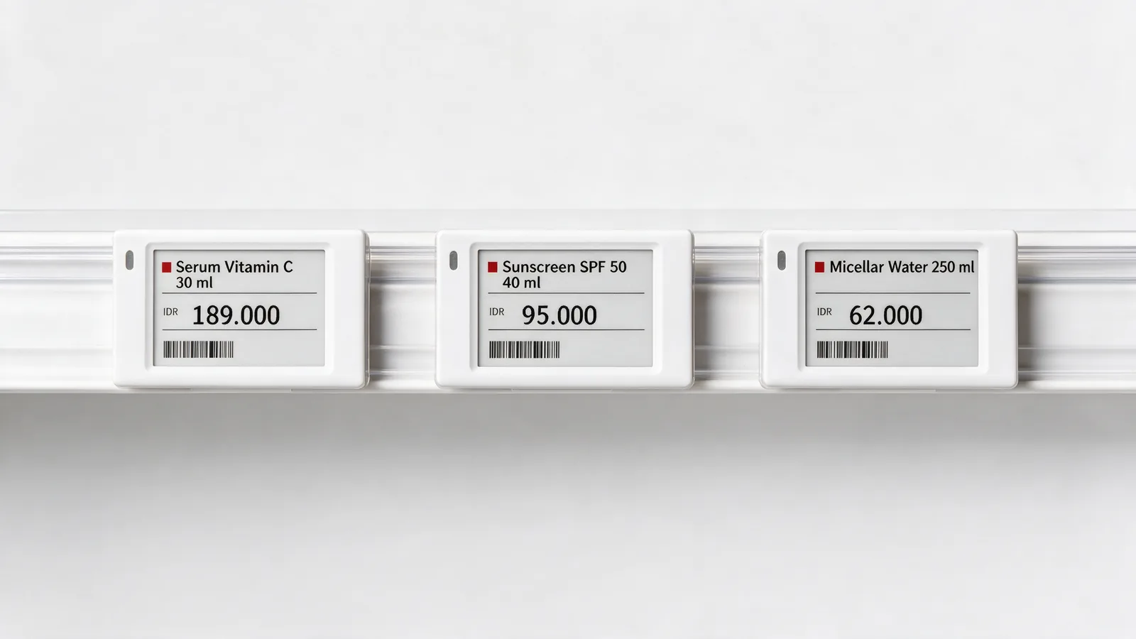 Three white electronic shelf labels in a clear rail on a white shelf edge, each showing a product name and price.